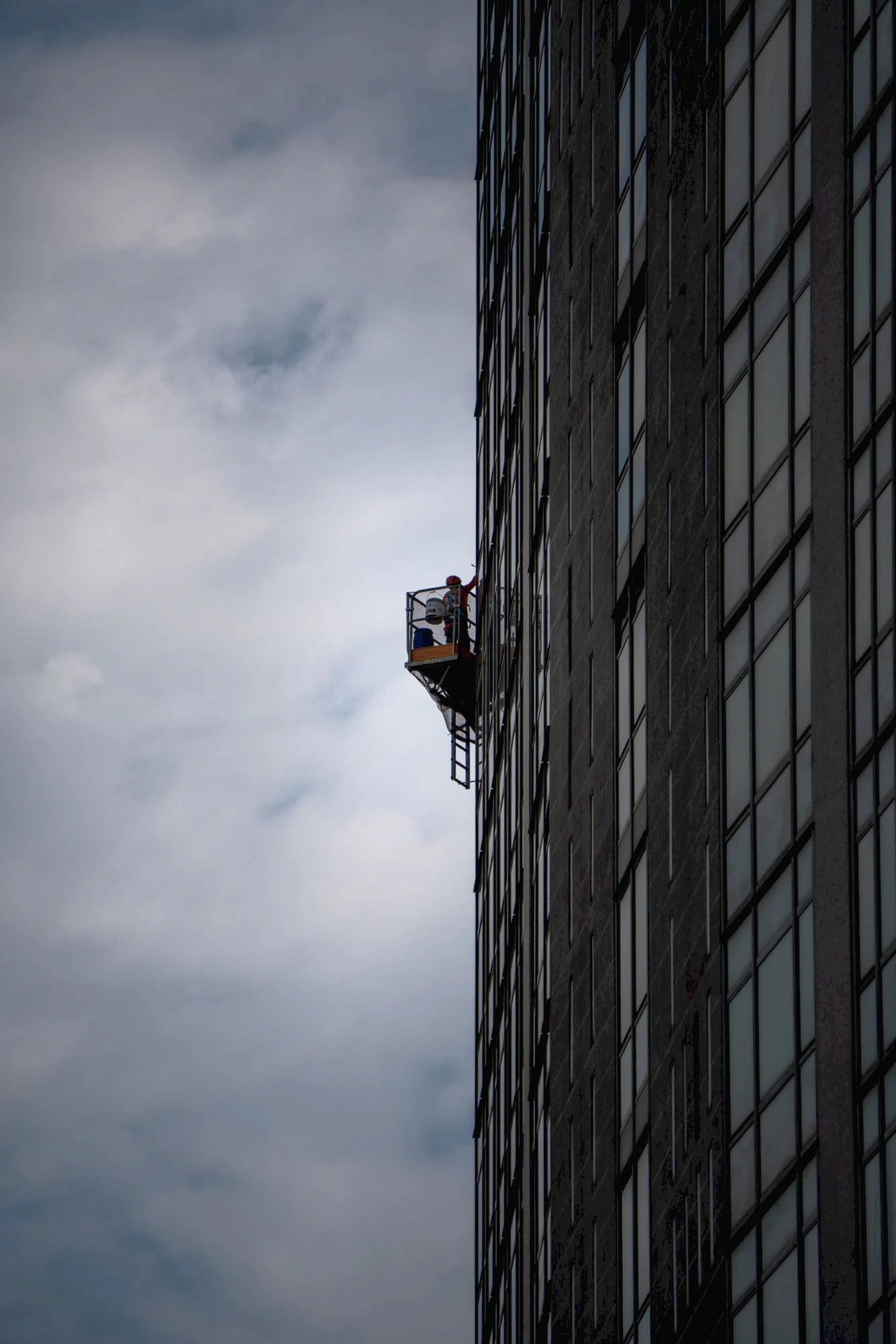A Riva restorer on a suspended platform along the façade of the Pirelli Tower, Milan